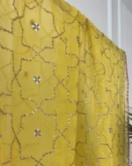 Detail of yellow bridal sharara set showing gota embroidered cuffs, gold brocade sharara skirt and sequin dupatta Pakistani bridal suit