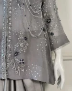 Side angle view of grey 3-piece Pakistani bridal suit on dress form showing heavy silver embroidery, pearl chain drape and satin trouser