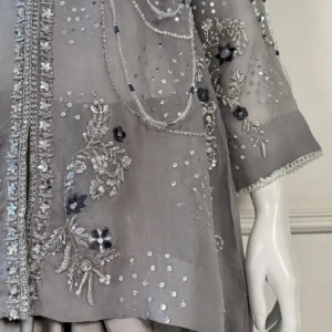 Side angle view of grey 3-piece Pakistani bridal suit on dress form showing heavy silver embroidery, pearl chain drape and satin trouser