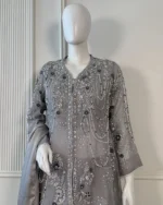 Grey organza Pakistani bridal suit on mannequin with silver zardozi embroidery, pearl bead chain drape and 3D navy floral appliqué front upper body view