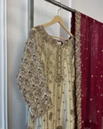 Gold tissue Pakistani bridal kurti with heavy maroon and gold zardozi sleeve embroidery and maroon chiffon dupatta with gold scalloped border — upper body view on hanger