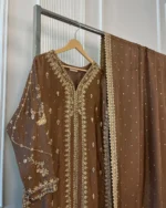 Side view of brown 3-piece Pakistani bridal suit with gold embroidery and matching pearl dot dupatta on display rack