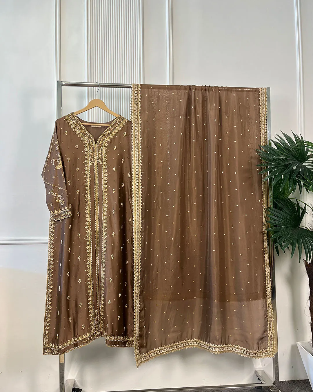Full view of 3-piece brown Pakistani bridal suit with gold embroidered kurti and pearl dot dupatta on clothing rack